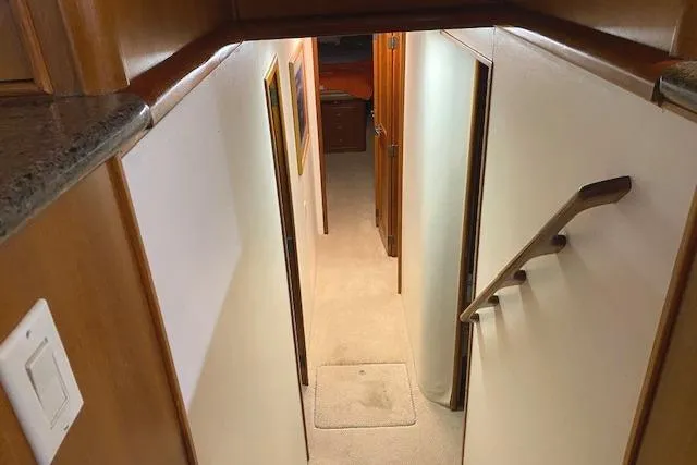 Slide: The Image of Interior hallway of a 1989 Buddy Davis 61 Sportfish yacht, featuring wood accents and carpeted flooring. - 15