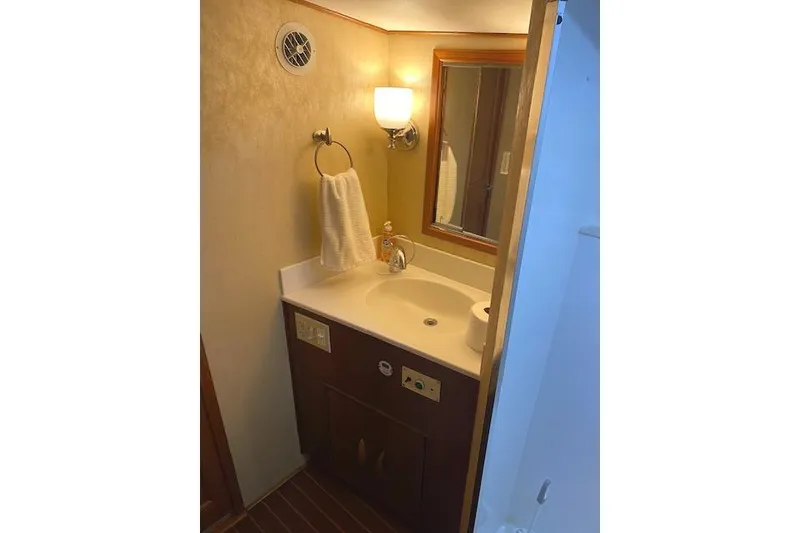 Slide: The Image of Bathroom vanity in 1989 Buddy Davis 61 Sportfish yacht, featuring sink, mirror, and towel holder. - 24