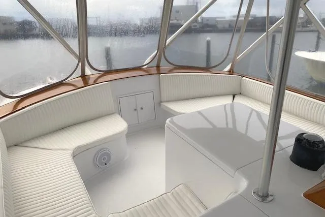 Slide: The Image of 1989 Buddy Davis 61 Sportfish boat interior with white seating and table, docked at marina. - 40