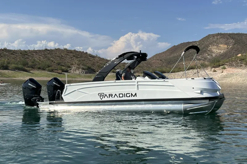 Slide: The Image of 2026 Paradigm Boats 27SST on a scenic lake with hills in the background. - 7