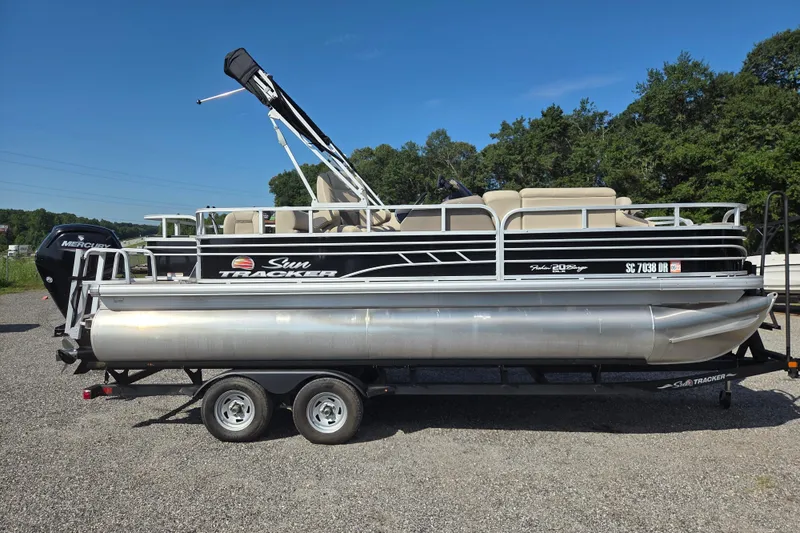 The Image of 2021 Sun Tracker Fishin' Barge 20 DLX pontoon boat on trailer, outdoors. - 0