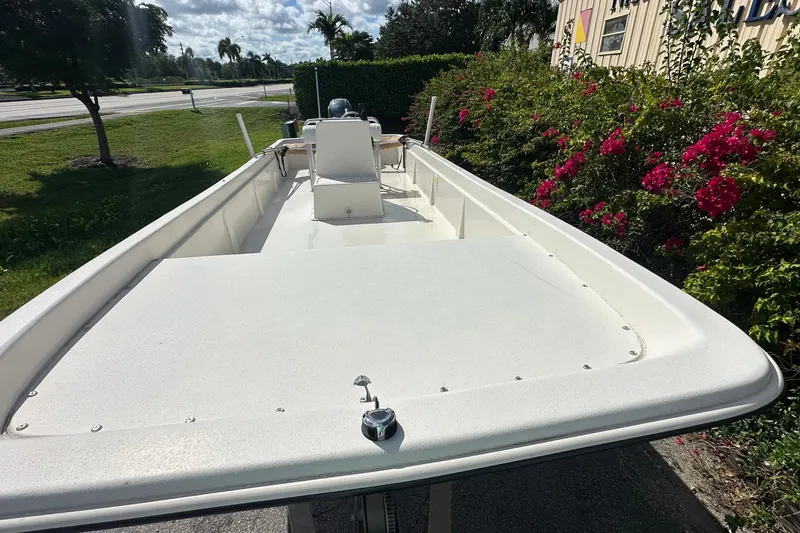Slide: The Image of 2024 Carolina Skiff E24 DLX CC boat, white deck, outdoor setting with flowers. - 10
