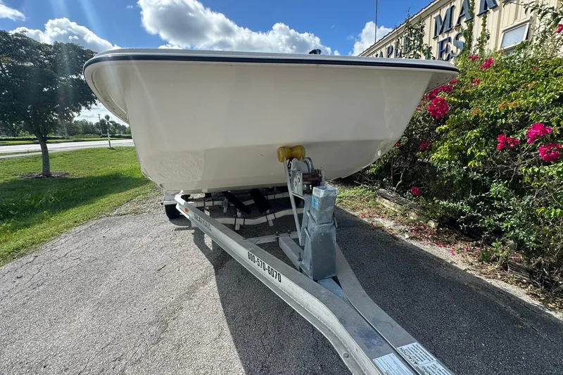 Slide: The Image of 2024 Carolina Skiff E24 DLX CC boat on trailer, parked near flowers and greenery. - 4
