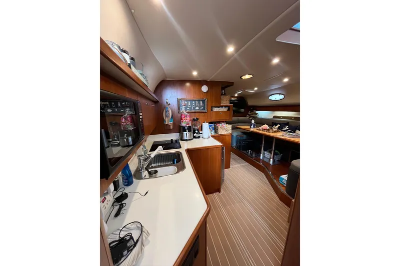 Slide: The Image of 1999 Tiara Yachts 4000 Express interior with kitchen and dining area, featuring wood finishes. - 29