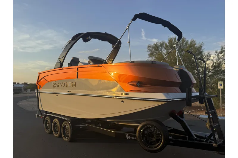 Slide: The Image of 2026 Paradigm 236 Surf boat on trailer, orange and white design, parked outdoors. - 1