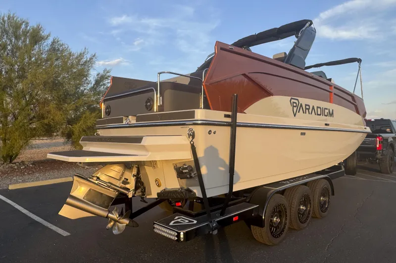 Slide: The Image of 2026 Paradigm 236 Surf boat on trailer, parked outdoors, showcasing sleek design and modern features. - 2