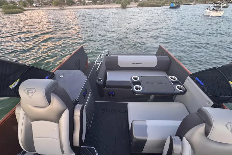 Slide: The Image of 2026 Paradigm 236 Surf boat interior with seating and table on a lake. - 6
