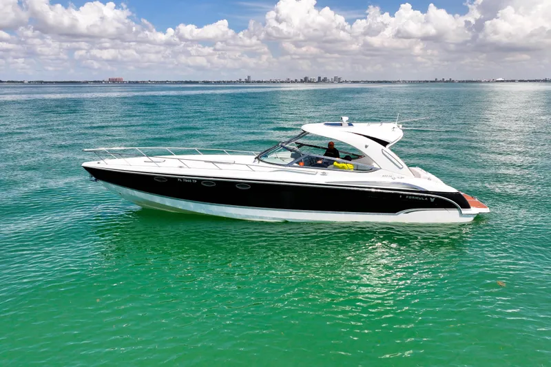 Slide: The Image of 2008 Formula 400 Super Sport boat cruising on clear turquoise water under a cloudy sky. - 6