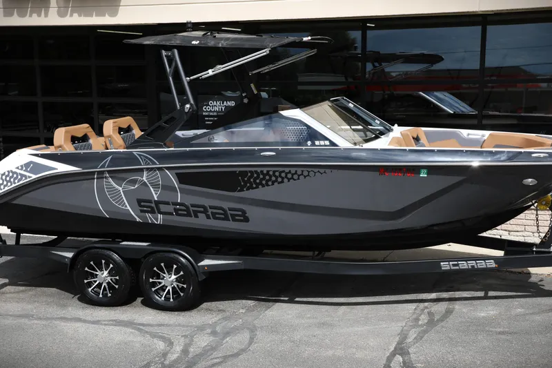 Slide: The Image of 2024 Scarab 235 Wake ID boat on trailer, sleek design, gray exterior. - 0