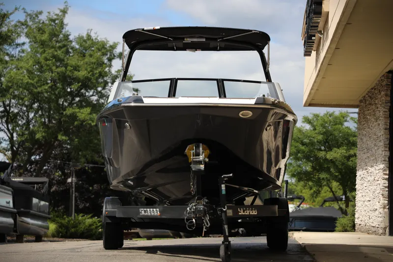 Slide: The Image of 2024 Scarab 235 Wake ID boat on trailer, parked outdoors near building. - 19