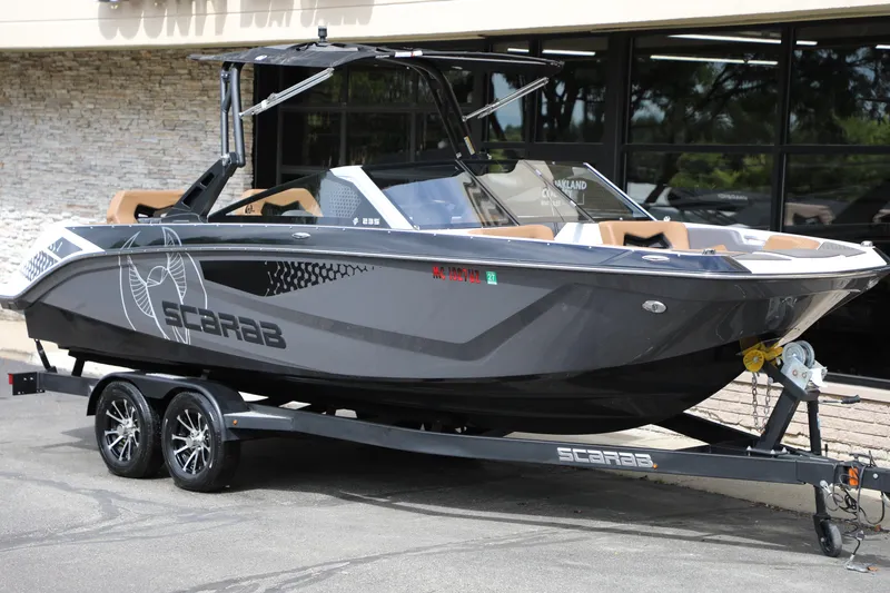 Slide: The Image of 2024 Scarab 235 Wake ID boat on trailer, sleek design, parked outdoors. - 22