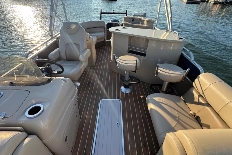 Slide: The Image of 2016 Xcursion 23RFE pontoon boat interior with seating and helm on water. - 10