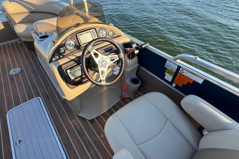 Slide: The Image of 2016 Xcursion 23RFE boat interior with steering wheel and control panel on water. - 12