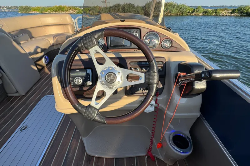 Slide: The Image of Steering console of 2016 Xcursion 23RFE boat with wooden accents and lake view. - 13