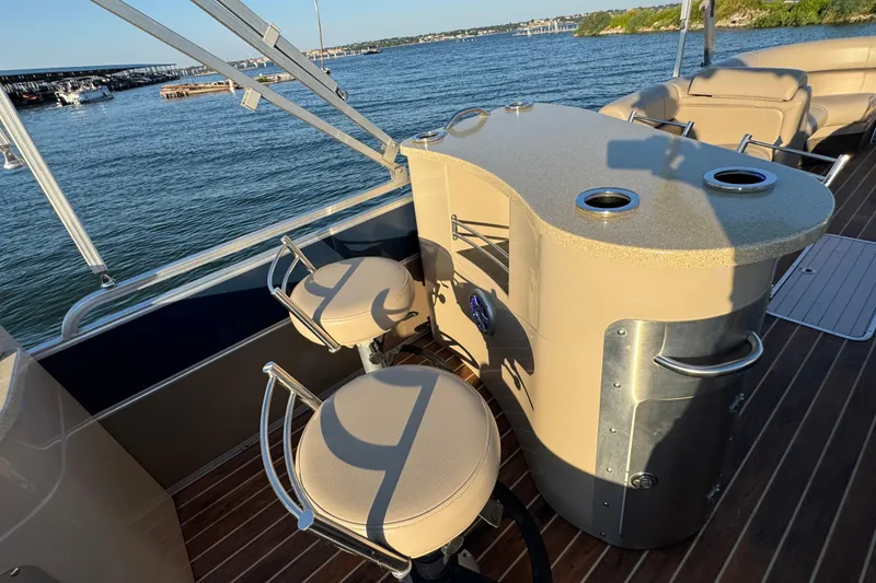 Slide: The Image of 2016 Xcursion 23RFE boat interior with bar stools and countertop on a sunny day. - 16