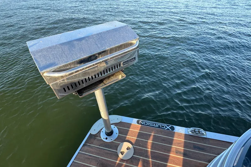 Slide: The Image of Boat deck with mounted grill on 2016 Xcursion 23RFE, overlooking calm water. - 22