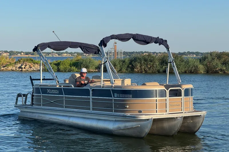 Slide: The Image of 2016 Xcursion 23RFE pontoon boat on a serene lake with lush greenery. - 4