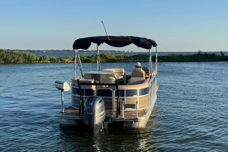 Slide: The Image of 2016 Xcursion 23RFE pontoon boat on a serene lake with lush greenery. - 6