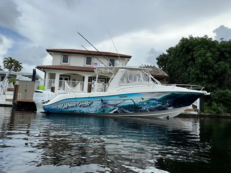 The Image of 2010 Hydra-Sports 3500 VX boat docked by a waterfront house, featuring vibrant wave graphics. - 0