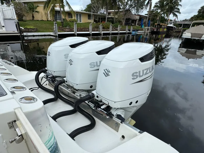 Slide: The Image of Triple Suzuki outboard engines on a 2010 Hydra-Sports 3500 VX boat docked by a canal. - 6