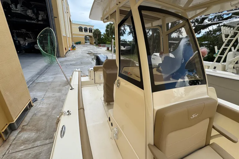 Slide: The Image of 2020 Scout 235 XSF boat docked, featuring beige seating and a fishing net. - 13