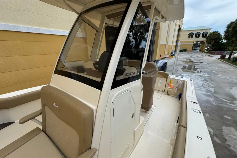 Slide: The Image of 2020 Scout 235 XSF boat with beige seating and sleek design, docked near a building. - 14