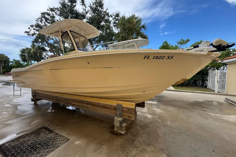 Slide: The Image of 2020 Scout 235 XSF boat on a lift, surrounded by trees and a clear sky. - 2