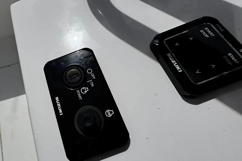 Slide: The Image of Control panel of a 2022 Whitewater 28 Open boat with Suzuki start-stop buttons. - 22