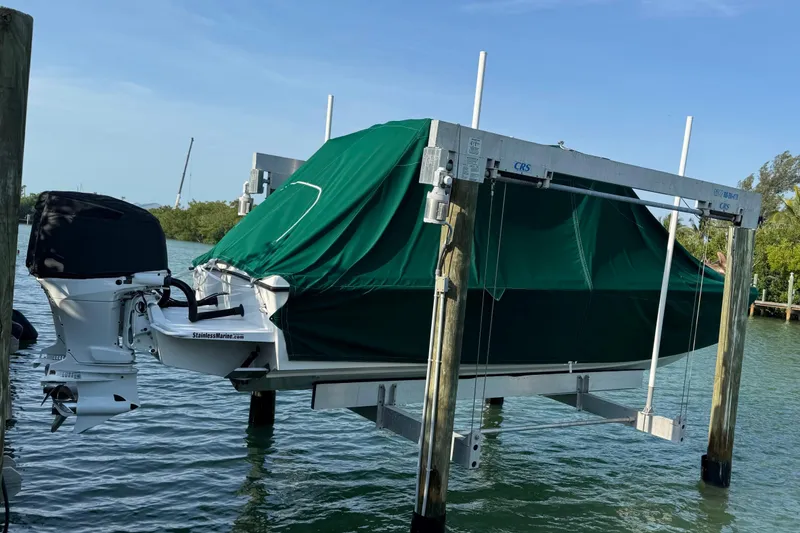 Slide: The Image of 2022 Whitewater 28 Open boat with green cover on a lift over water. - 3