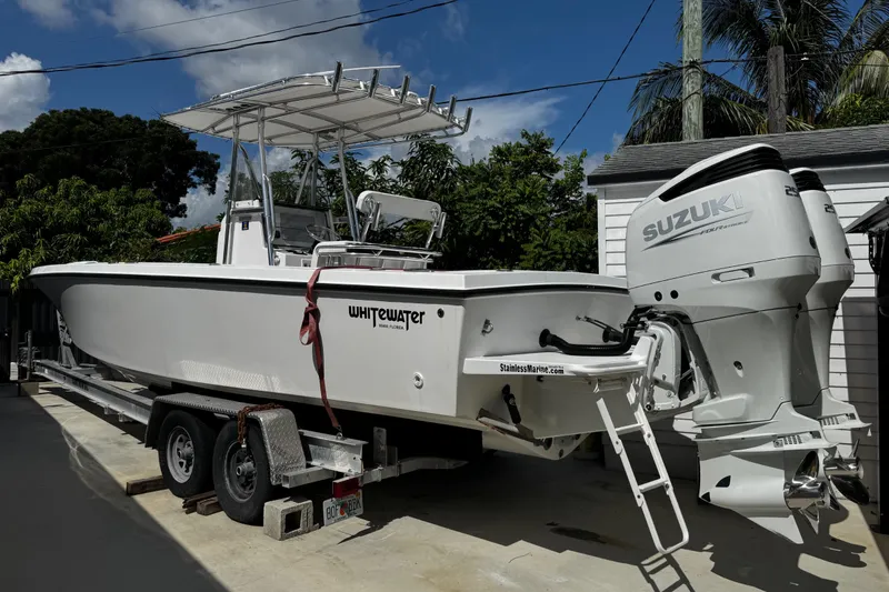 Slide: The Image of 2022 Whitewater 28 Open boat with Suzuki engines on a trailer, parked outdoors. - 4