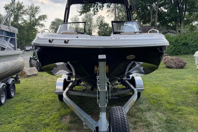 Slide: The Image of 2020 Hurricane SunDeck 191 OB boat on trailer, parked on grass with trees in background. - 2
