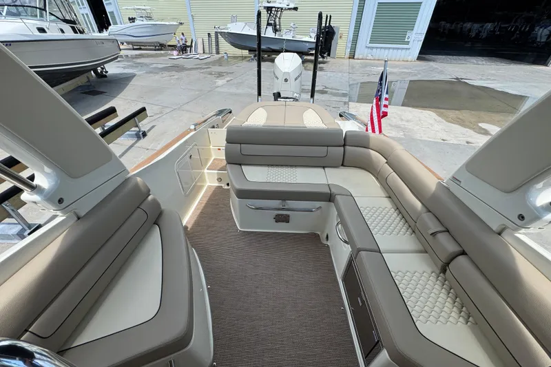Slide: The Image of 2023 Chris-Craft Launch 25 GT boat interior with beige seating and American flag. - 15