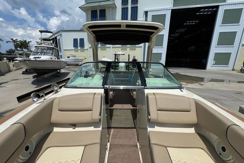 Slide: The Image of 2023 Chris-Craft Launch 25 GT boat interior with beige seating, docked near a marina. - 9