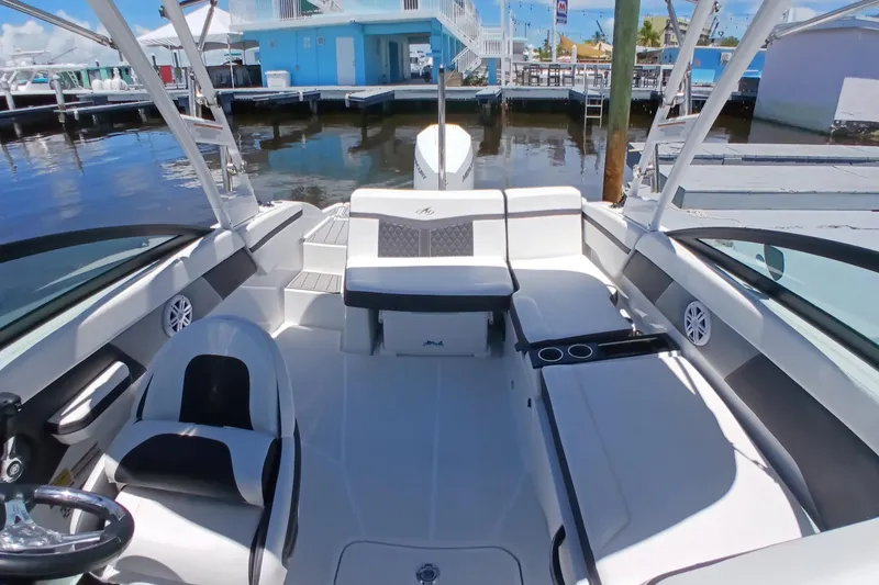 Slide: The Image of 2023 Monterey 225 boat interior with sleek seating and modern design at a marina. - 11