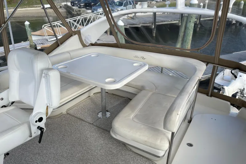 Slide: The Image of 2000 Sea Ray 400 Sedan Bridge interior with white seating and table, docked at marina. - 13