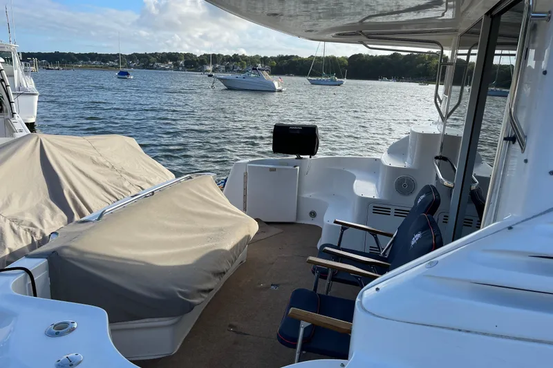 Slide: The Image of 2000 Sea Ray 400 Sedan Bridge yacht interior with covered seating, overlooking a serene marina. - 4