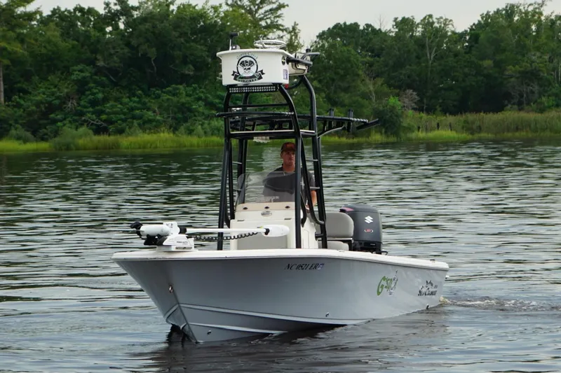 Slide: The Image of 2020 Sea Chaser 23 LX boat navigating a calm river with lush green background. - 2