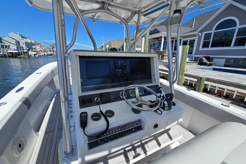 Slide: The Image of 2004 SeaVee 340B boat console with steering wheel and navigation equipment, docked by waterfront homes. - 11