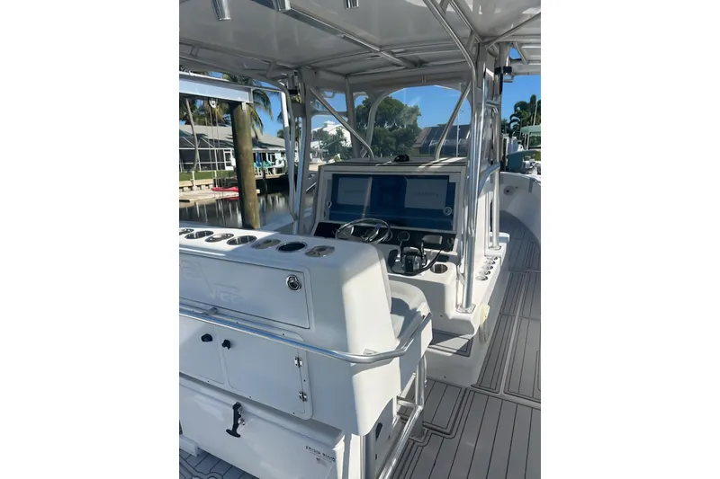 Slide: The Image of 2004 SeaVee 340B boat interior with helm, controls, and seating, docked near waterfront homes. - 22