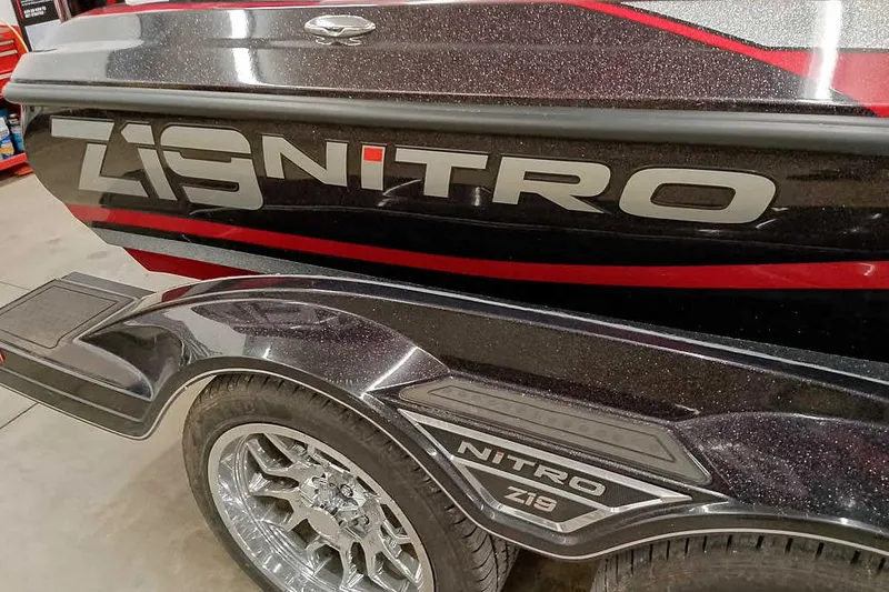 Slide: The Image of 2022 Nitro Z19 SC boat with sleek design and chrome wheels in a showroom. - 4