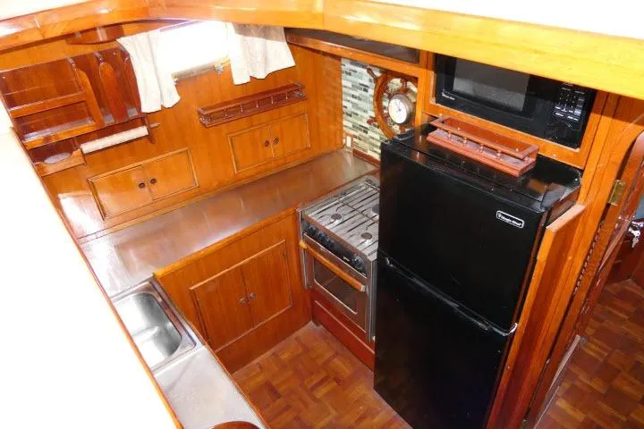 Slide: The Image of 1983 CHB 45 boat kitchen with wood cabinetry, stove, fridge, and microwave. - 12