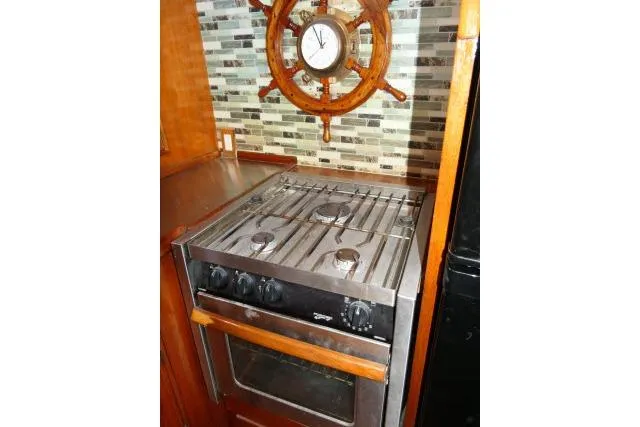 Slide: The Image of Vintage CHB 45 yacht kitchen with stove, nautical clock, and tiled backsplash, 1983 model. - 15