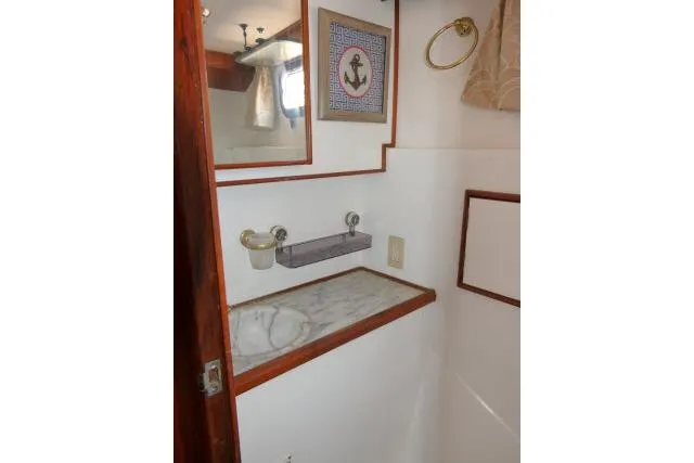 Slide: The Image of 1983 CHB 45 boat interior with marble sink, mirror, and nautical decor. - 27