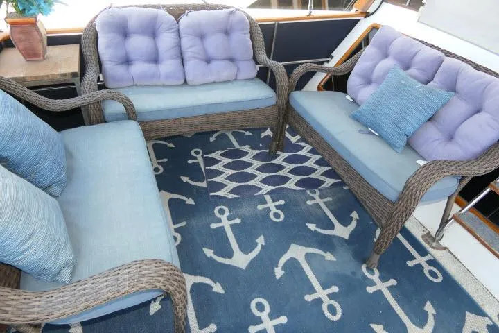 Slide: The Image of Wicker seating with blue cushions on a nautical-themed rug in a 1983 CHB 45 boat. - 44