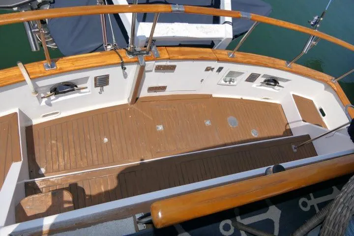 Slide: The Image of Wooden deck of a 1983 CHB 45 boat, featuring polished railings and marine equipment. - 45
