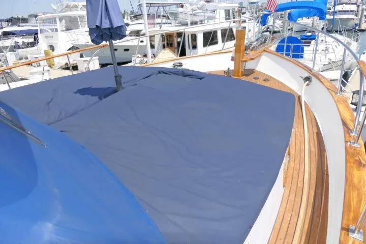 Slide: The Image of 1983 CHB 45 yacht deck with blue cover, docked at marina. - 47