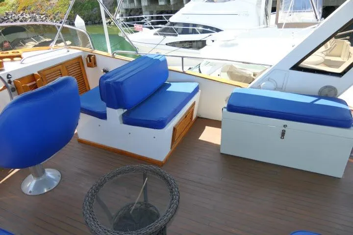 Slide: The Image of 1983 CHB 45 yacht deck with blue seating and wooden flooring. - 55