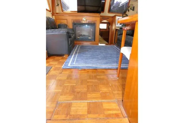 Slide: The Image of Interior of 1983 CHB 45 boat with wood flooring, blue rug, and cozy seating area. - 6