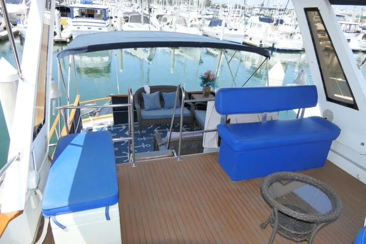 Slide: The Image of 1983 CHB 45 yacht deck with blue seating, marina view, and elegant outdoor furniture. - 60