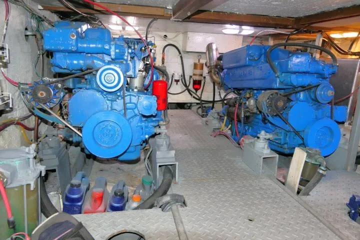 Slide: The Image of Engine room of 1983 CHB 45 boat with dual blue engines and mechanical components. - 62